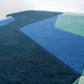 Close-up of a geometric patterned rug with blue and green colors.
