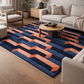 Living room with a blue and orange geometric rug, beige sofa, and wooden coffee table.