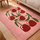 Pink rug with red cherry design on a wooden floor
