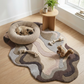 Dog resting on a knitted pet bed on a patterned rug in a room with a small table and plants.