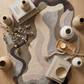 Decorative rug with wavy pattern on a wooden floor, surrounded by vases and books.