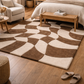 Patterned brown and beige rug on a wooden floor with furniture in a room.