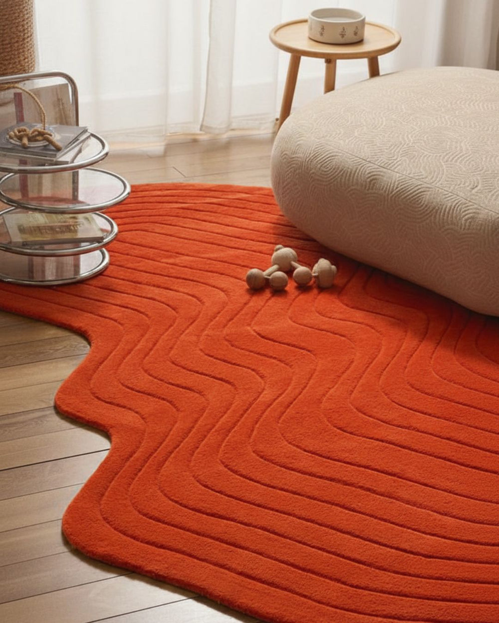Orange textured rug on a wooden floor with a glass side table and white cushion.