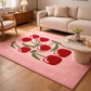 Living room with a pink rug featuring red tulip design, beige sofa, and wooden coffee table.