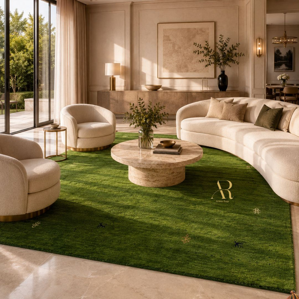 A large green area rug with a subtle grass texture and small gold monogram details, styled in a luxurious modern living room with cream-colored curved sofas and a round stone coffee table.
