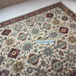 Decorative rug with intricate patterns on a tiled floor, featuring the brand 'Artista Rugs'.