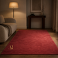 Red rug with a logo in a dimly lit room with a lamp and sofa.
