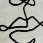 Black abstract line drawing on a textured gray background