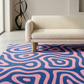 Living room with a patterned pink and blue rug, beige sofa, and decorative sculpture.