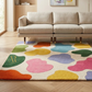 Colorful abstract rug on a wooden floor in a living room setting with a beige sofa.