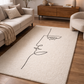 Beige rug with a black line art design of a face in a living room setting.