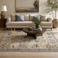Living room with a beige sofa, round wooden coffee table, and decorative rug.