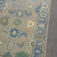 Close-up of a floral patterned rug with blue and green colors on a gray surface.