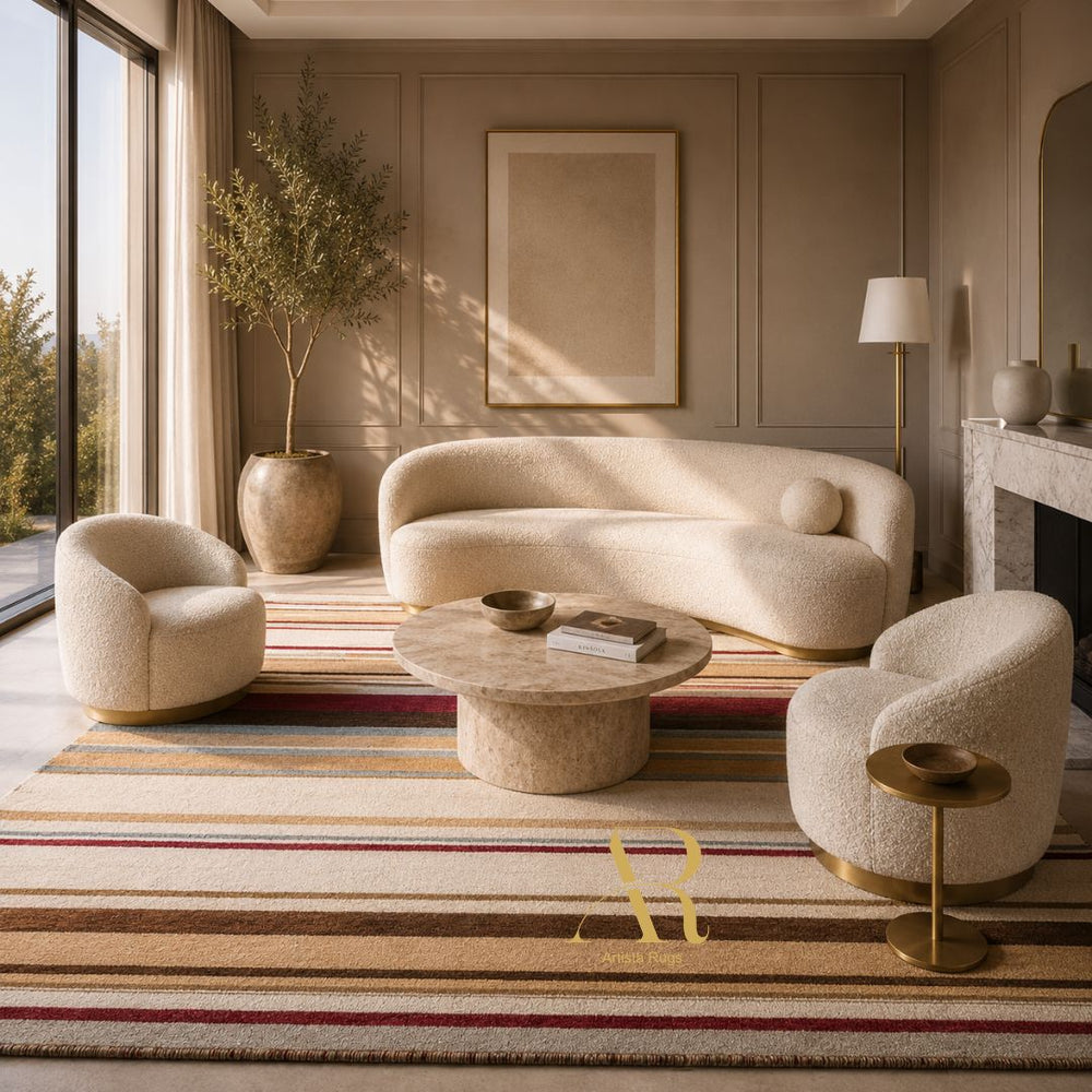 A styled interior scene with a cream boucle sofa, two matching armchairs, a round stone coffee table, a striped area rug, and a tall potted tree in a warm, sunlit room.