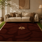A large dark red area rug with a beige floral pattern and central medallion, styled in a modern living room setting with a beige sofa, decorative pillows, and a lamp.