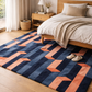 Geometric patterned rug in a bedroom with a bed and nightstand.