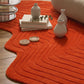 Orange textured rug with decorative items on a wooden floor