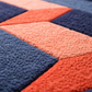 Close-up of a textured fabric with a geometric pattern in blue, orange, and pink.