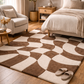 Patterned brown and beige rug in a living room with a sofa, coffee table, and bed.
