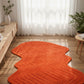 Orange wavy rug on a wooden floor with a light curtain background