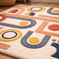 Geometric patterned rug with colorful shapes on a wooden floor.