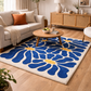 Living room with a blue floral rug, beige sofa, and wooden coffee table.