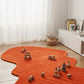 Orange wavy rug on a wooden floor with toys around it, in a room with white curtains and a white cabinet.