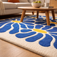 Blue floral patterned rug on a wooden floor with a coffee table and sofa in the background.