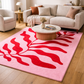 Living room with a pink rug featuring red abstract designs, a beige sofa, and a coffee table.