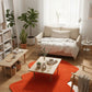 Modern living room with a beige sofa, wooden coffee table, and orange rug.