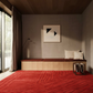 Modern interior with a wooden bench, red rug, and abstract art on the wall.