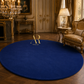 A large round royal blue area rug with a gold 'Artsie Royal' monogram logo in the center, displayed in an elegant, vintage-style room with gold furniture and wood floors.