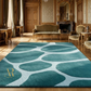 Luxurious room with a large teal and white patterned rug, wooden furniture, and ornate decor.