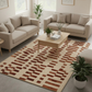 Living room with beige sofas, a coffee table, and a patterned rug.