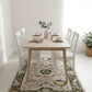 Dining room with wooden table and white chairs on a floral rug