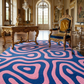 Luxurious room with ornate furniture and a colorful pink and blue rug.