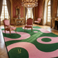 Luxurious room with pink and green patterned rug, ornate chairs, and chandelier.