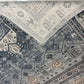 Close-up of a patterned rug with geometric designs in blue, beige, and gray.