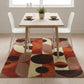 Dining room with a colorful geometric rug, wooden table, and white chairs.