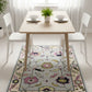 Dining table with chairs on a decorative rug in a room with light-colored walls and floor.