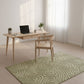 Modern home office with a desk, chair, and green patterned rug.