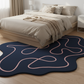 Modern bedroom with a blue rug featuring pink abstract patterns.