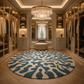 A luxury walk-in closet with built-in glass wardrobe doors, warm lighting, a large round blue and cream patterned rug, a beige ottoman, and two crystal chandeliers.