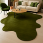 Green rug on a wooden floor with a beige sofa and green chairs in the background.