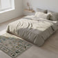 Neatly made bed with light-colored bedding in a bright bedroom.