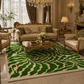An ornate living room featuring a large area rug with a bold green and cream wavy leaf-like pattern, styled with gold-framed sofas, a glass coffee table, and a crystal chandelier.