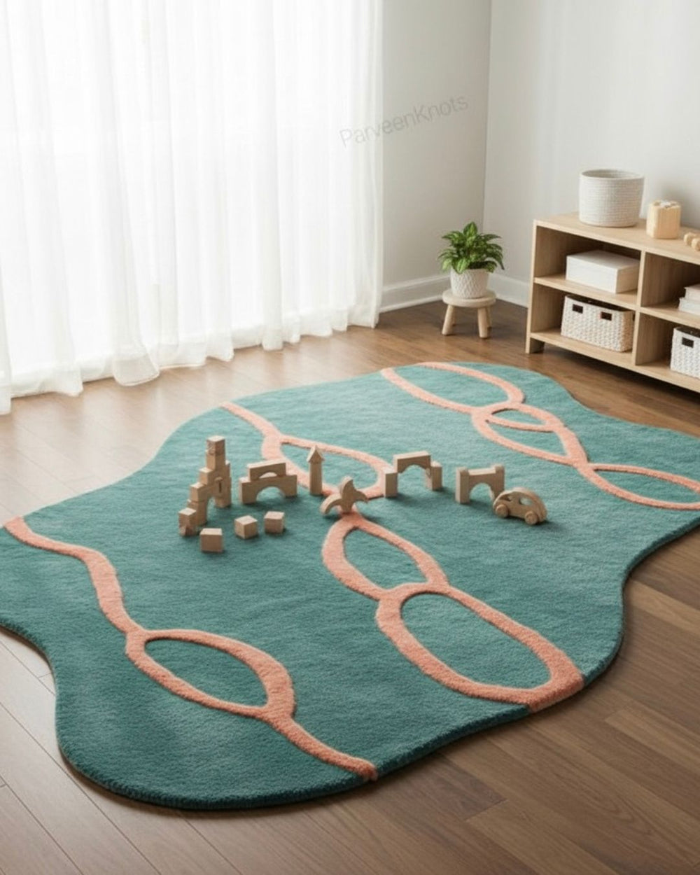 Teal and pink rug with toy blocks on a wooden floor in a room with white curtains.