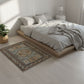 Bedroom with a wooden platform bed, white bedding, and a decorative rug on a light wood floor.