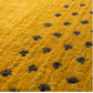 A close-up of a textured mustard yellow rug with a repeating pattern of dark charcoal gray star-like motifs.