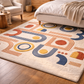 Colorful geometric-patterned rug on a wooden floor in a living room setting.